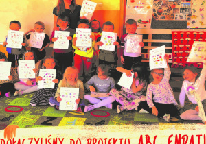 Zdjęcie grupy zielonej dzieci pozują w ręce mają kartę pracy zajęć o cukrzycy: "Bateria", dzieci wraz z nauczycielem uśmiechają się do zdjęcia poniżej napis dołączyliśmy do projektu ABC Empatii